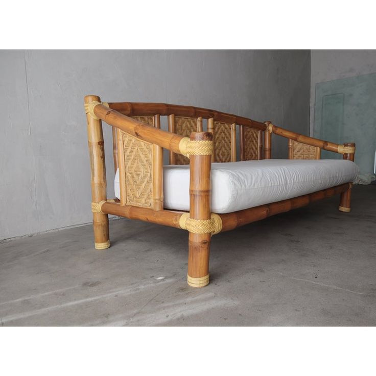 a bed frame made out of bamboo with white mattress and pillows on top of it