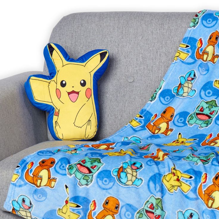 a blanket and pillow on a couch with the pokemon characters printed on it, along with a stuffed toy