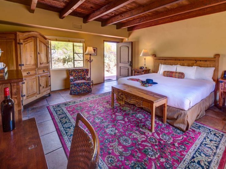 a bedroom with a large bed and colorful rugs on the floor in front of it