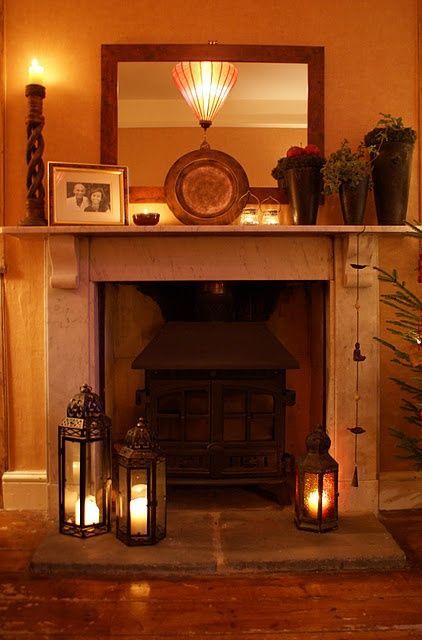 a fire place with candles and pictures on the mantle