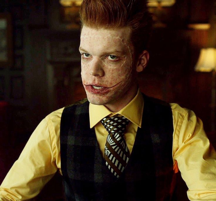 a young man with red hair wearing a yellow shirt and black plaid tie is looking at the camera