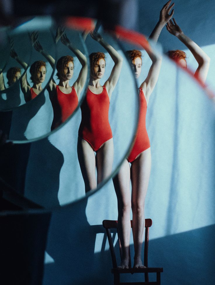 a woman in a red leotard standing on a chair