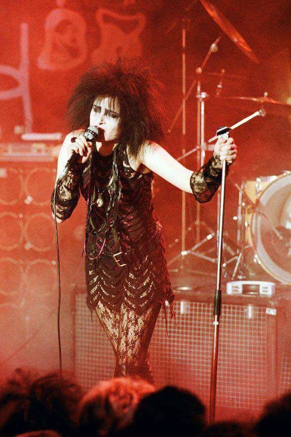 a woman on stage holding a microphone in front of an audience at a rock concert