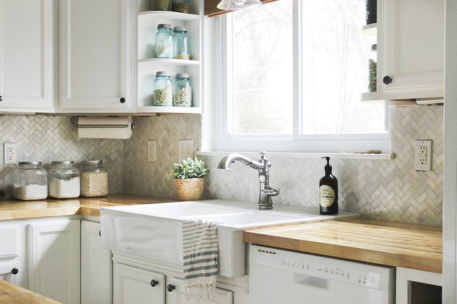 a kitchen with white cabinets and wooden counter tops, including a dishwasher in the center