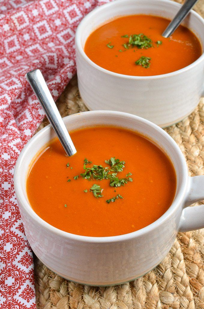 two white bowls filled with tomato soup and garnished with parsley