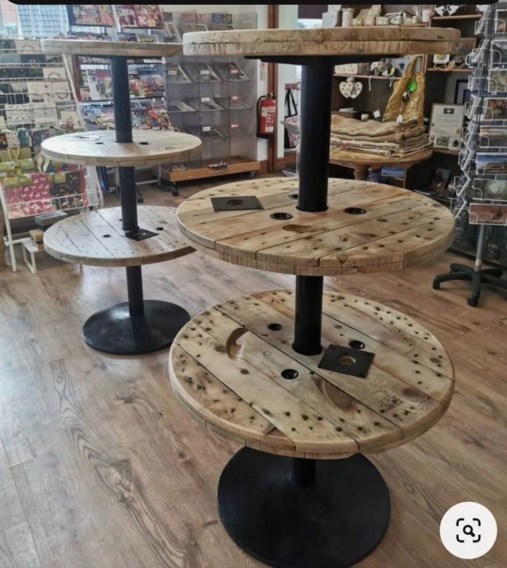 three tiered wooden table in a store with black metal legs and round wood shelves