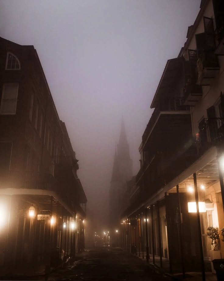 a foggy city street with buildings and lights