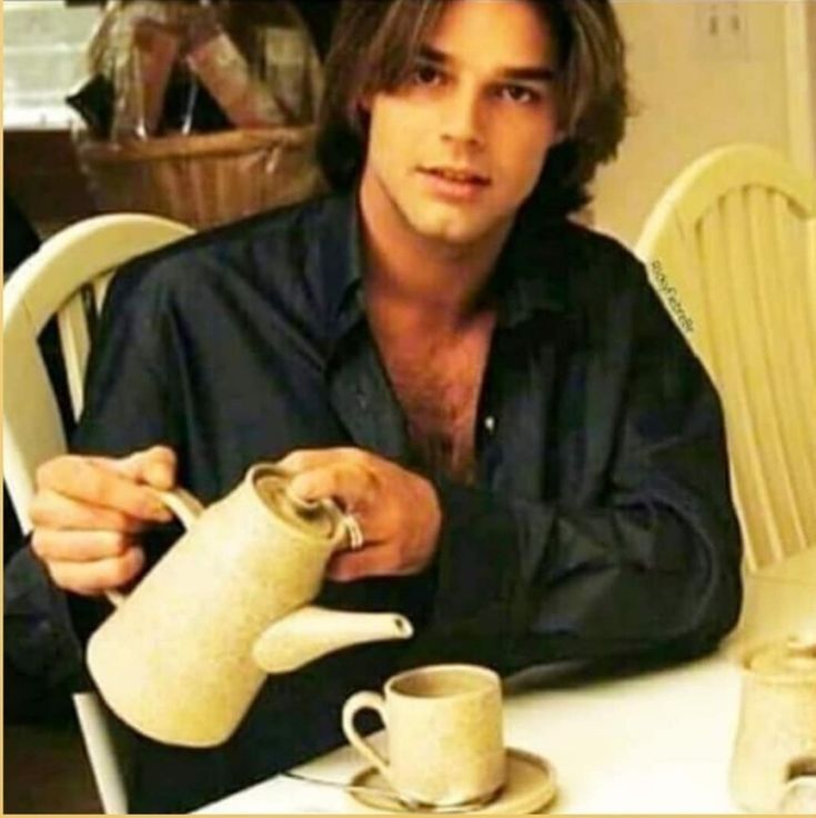 a man sitting at a table with a teapot and cup in front of him