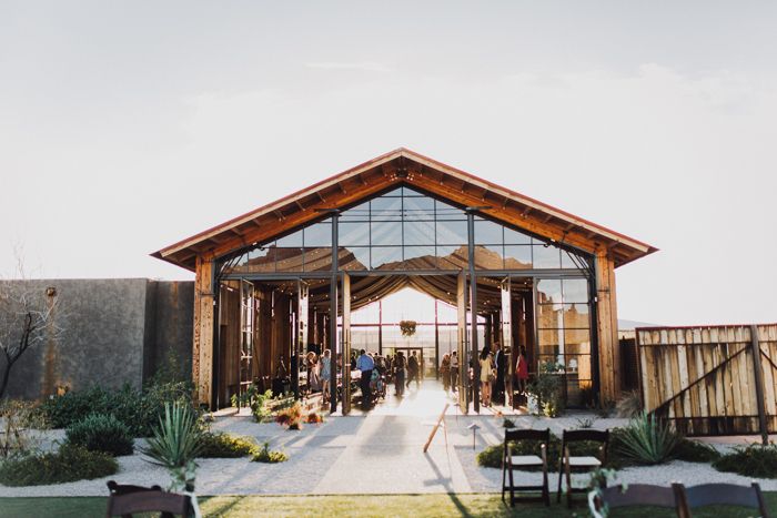 an outdoor venue with chairs and tables in front of the entrance to the building, surrounded by greenery