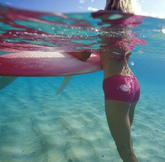 a woman in pink swimsuit holding a surfboard under water