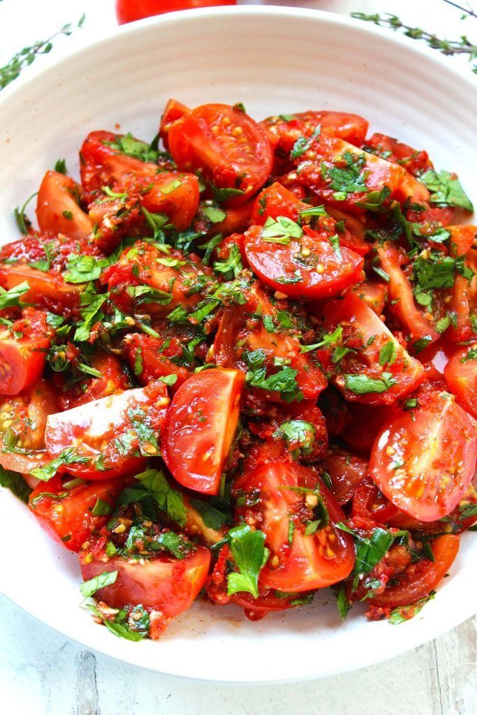 a white bowl filled with sliced tomatoes and herbs