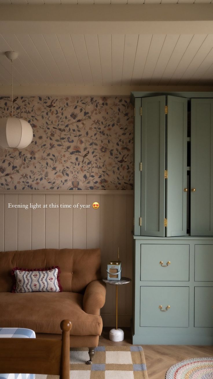 a living room filled with furniture and walls covered in floral wallpaper, next to a brown couch