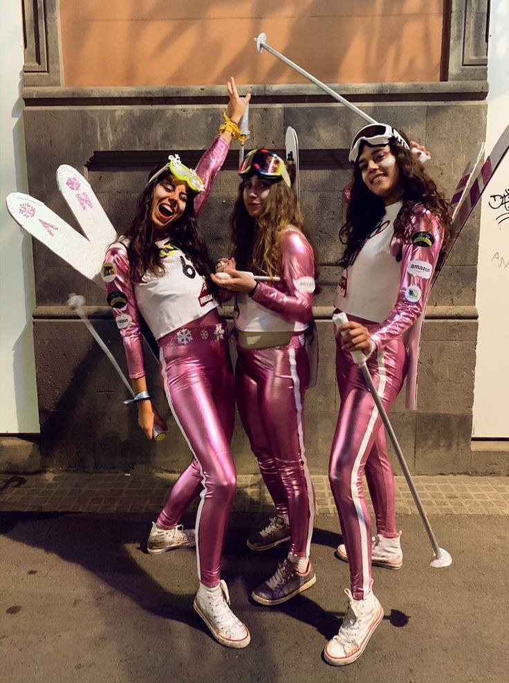 three girls dressed in pink and white posing for the camera with their skis on