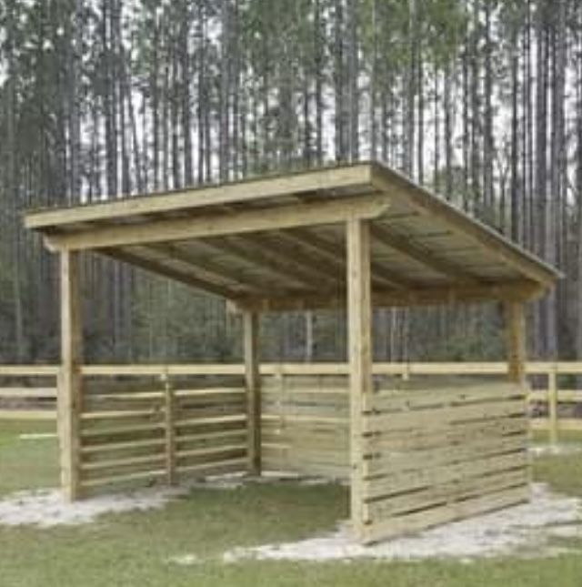 a wooden shelter in the middle of a field