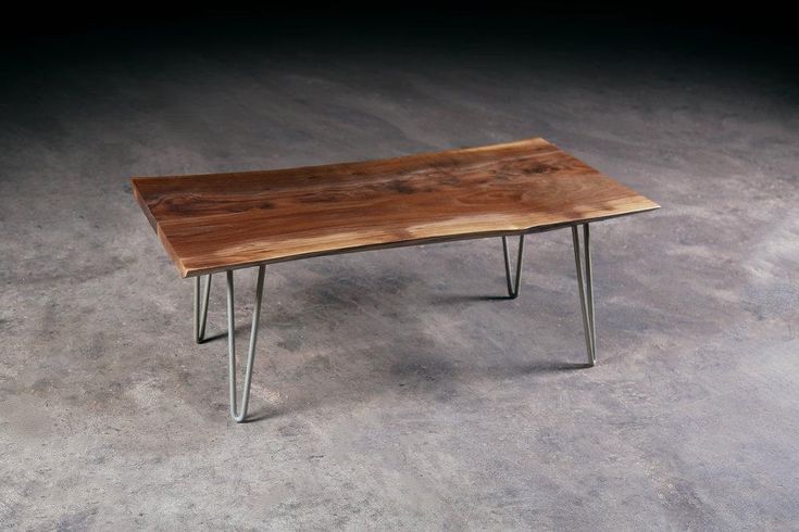 a wooden table sitting on top of a cement floor next to a metal leg rest