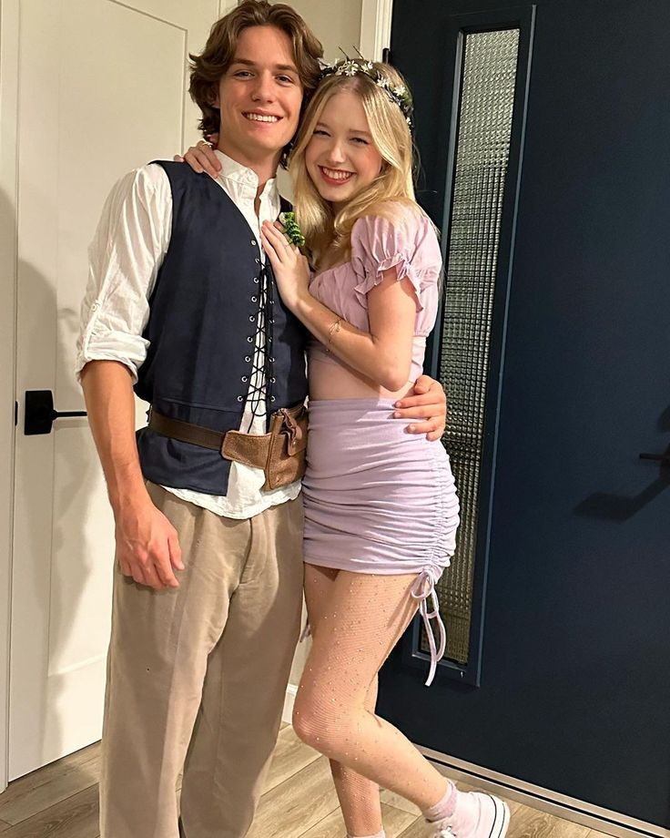 a young man and woman posing for a photo in front of a blue door wearing costumes