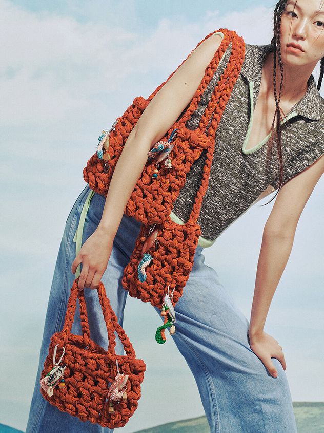 a woman is holding a crocheted orange purse