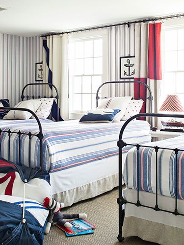 a bed room with two beds next to each other and striped curtains on the windows