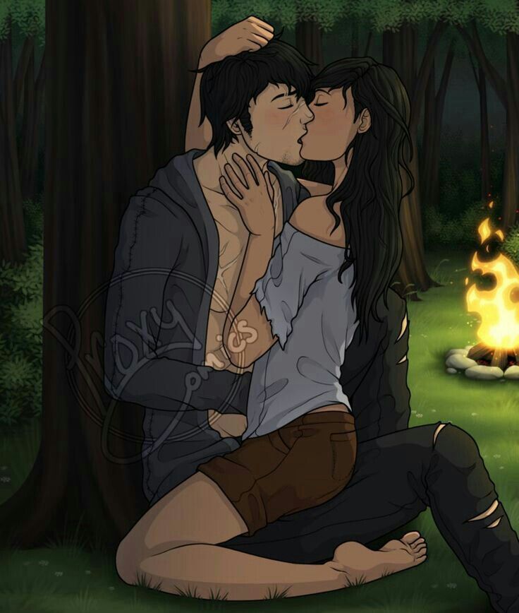 two people sitting on the ground in front of a campfire and one is kissing