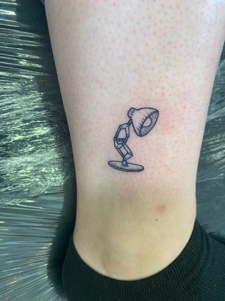 a small tattoo on the ankle of a woman's leg with a lamp in it