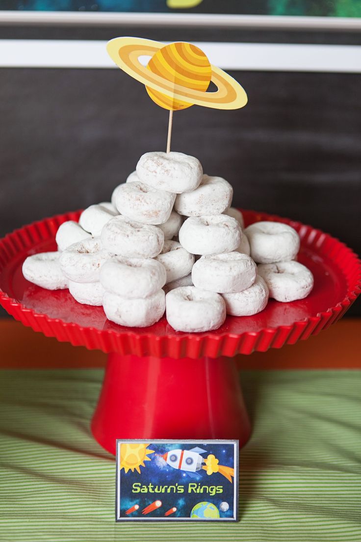 a red plate topped with white doughnuts on top of a table