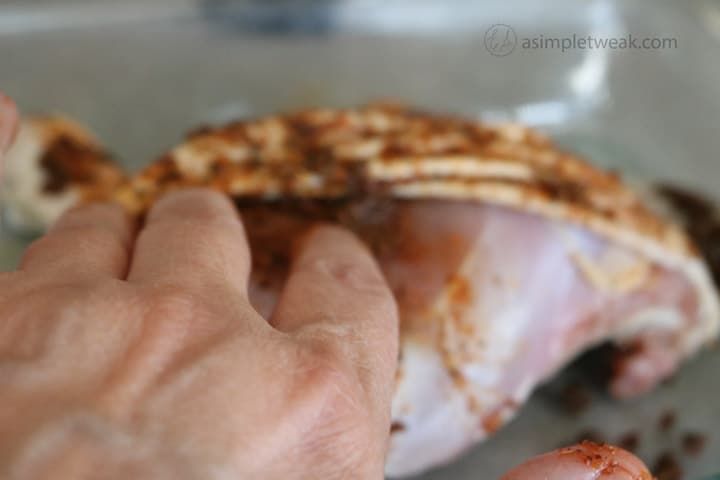 a person holding their left hand over a piece of meat