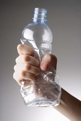 a person holding a plastic water bottle in their right hand, with the other hand on top of it