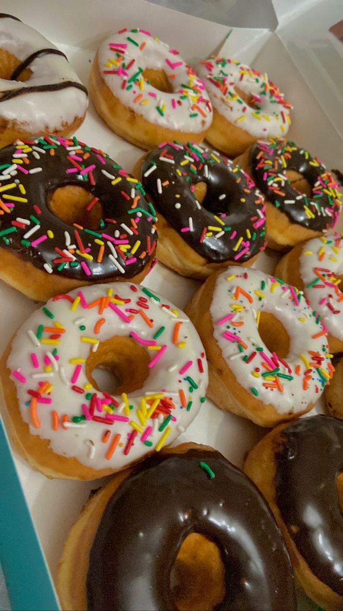 a box filled with lots of donuts covered in frosting and sprinkles