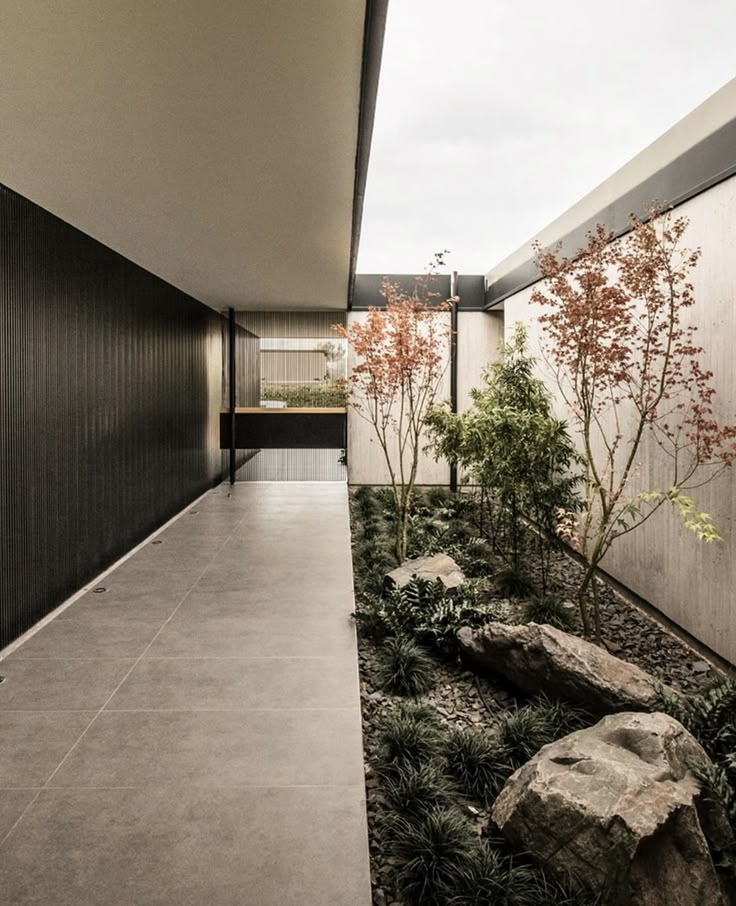 the walkway is lined with rocks and plants in front of an open area that looks like a courtyard