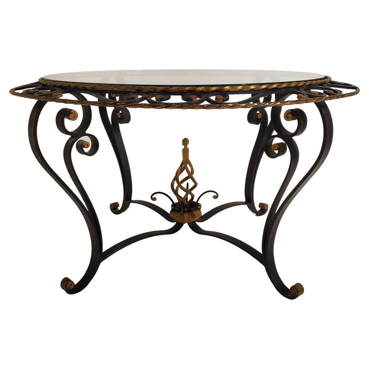 a table that has a glass top and metal legs on it with an ornate design