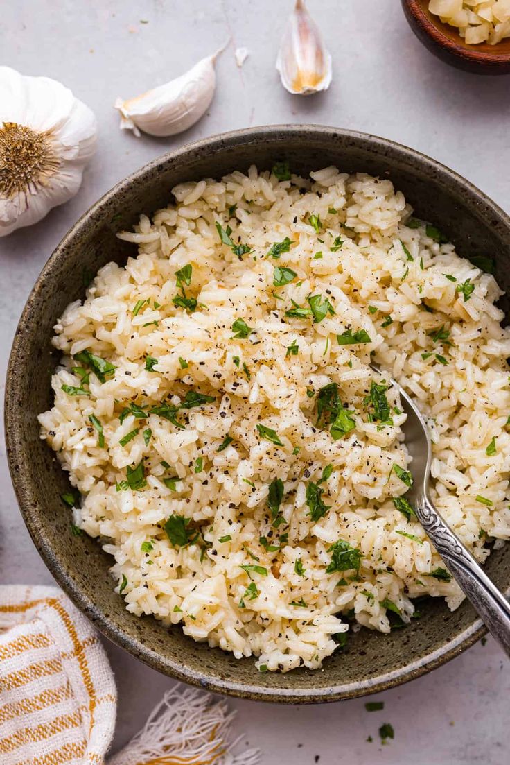 a bowl filled with rice and herbs next to garlic