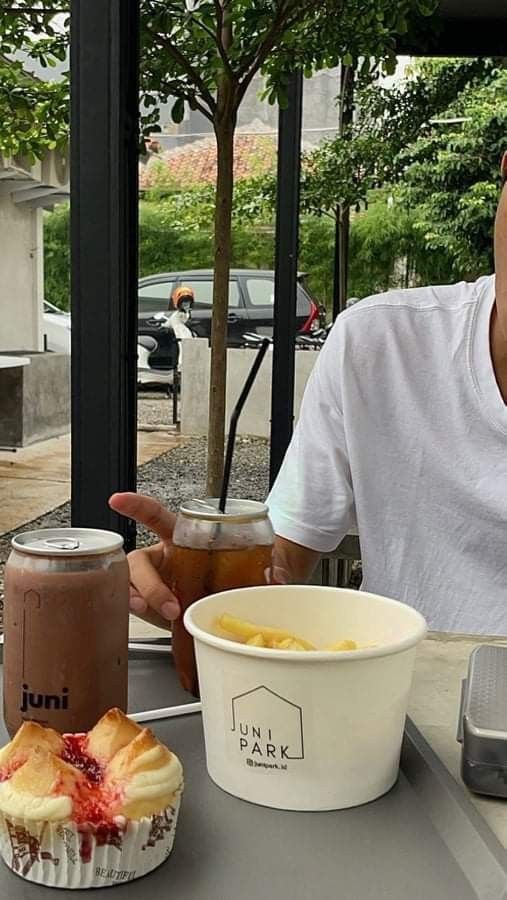 a man sitting at a table with two cups of coffee and a muffin in front of him