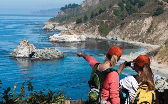 three people looking out at the ocean and cliffs