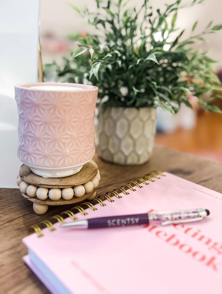 a pen is sitting on top of a notebook next to a potted plant