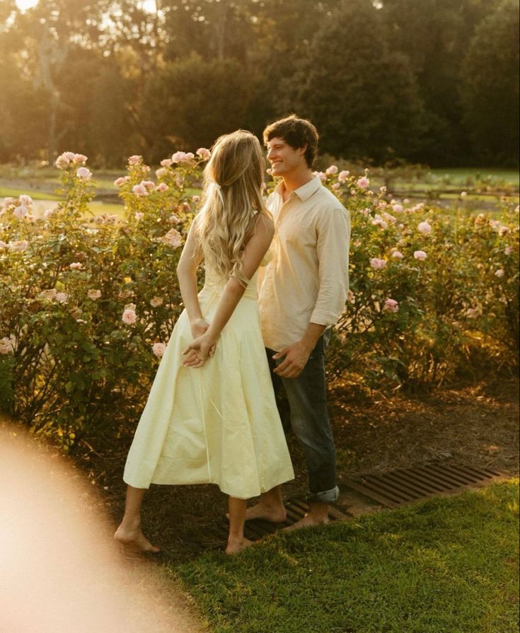 a man and woman standing next to each other in front of flowers