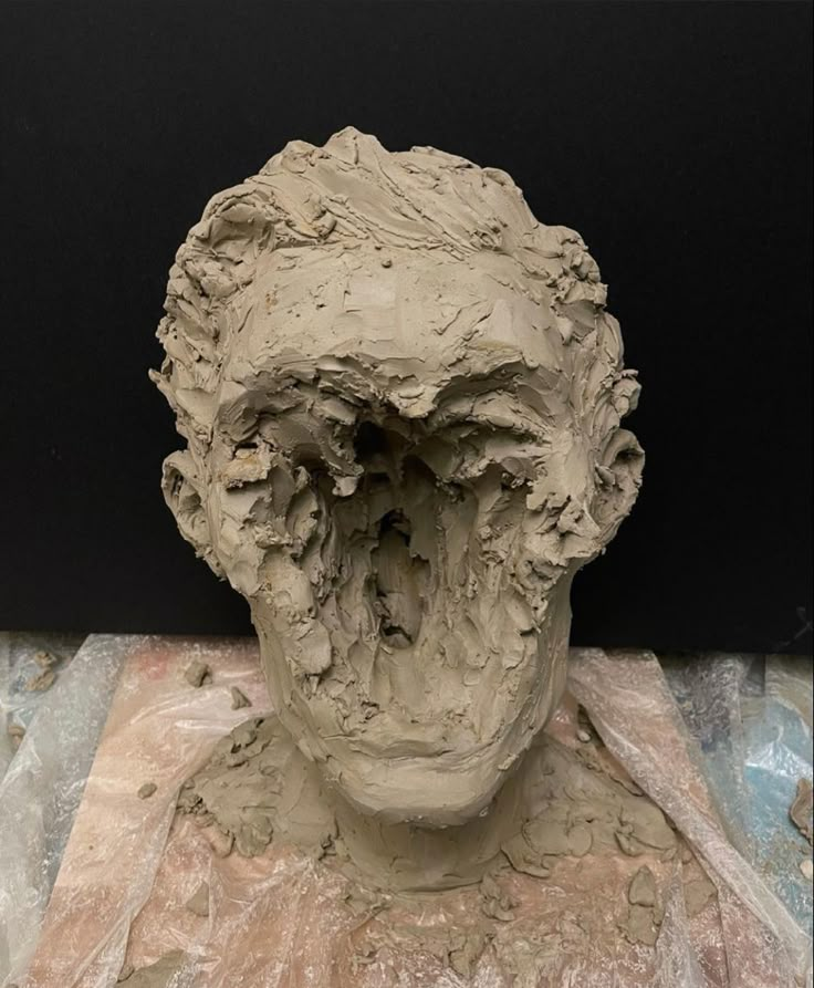 a clay sculpture of a man's head with his mouth open