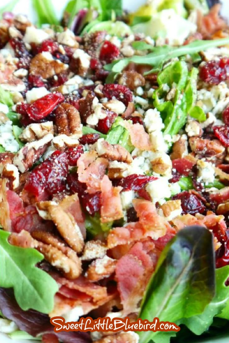 a salad with bacon, lettuce and cranberries in it on a white plate