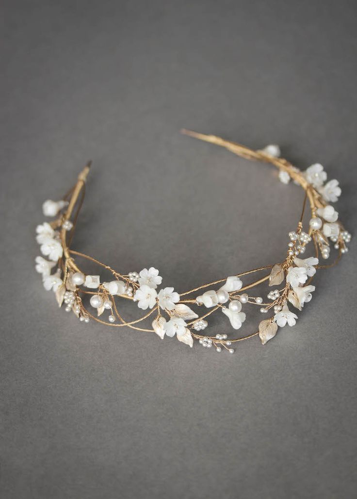 a gold headband with white flowers and leaves on it, sitting on a gray surface