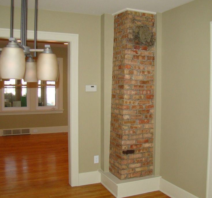 an empty room with a brick wall and wood flooring in the corner, along with three lights