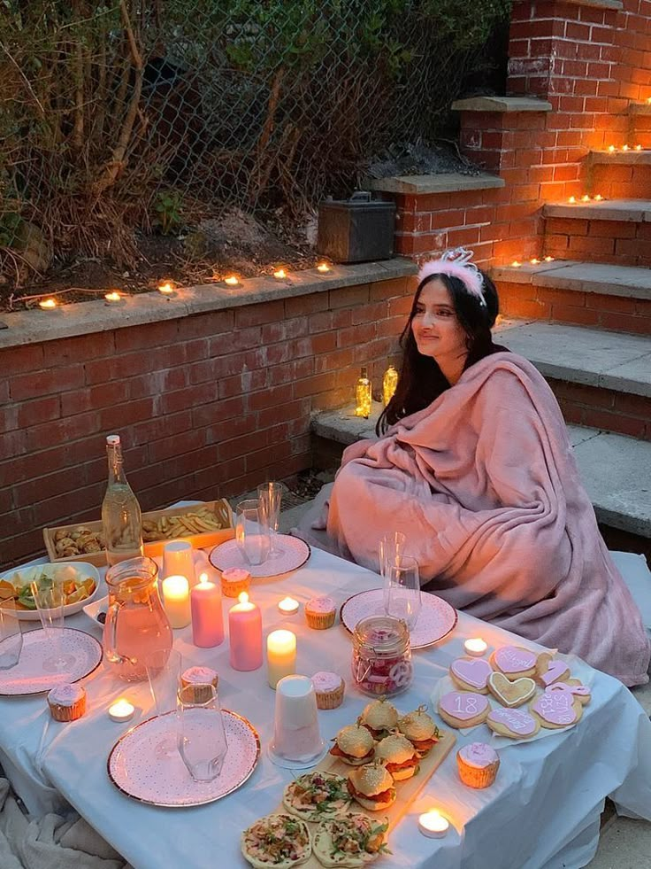 a woman sitting at a table with food and candles on it in front of her