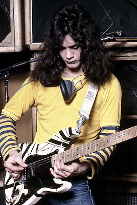 a man with long hair playing an electric guitar in front of a microphone and amp