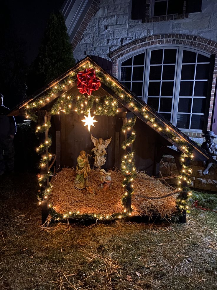 a christmas nativity scene in front of a house with lights and decorations on the roof