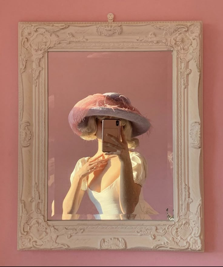 a woman taking a selfie in front of a mirror with a hat on her head