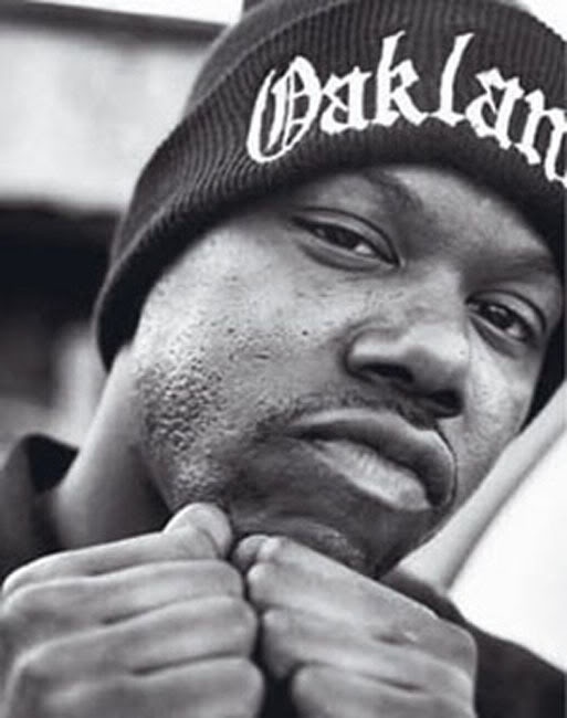 a black and white photo of a man wearing a beanie with the word oakland on it