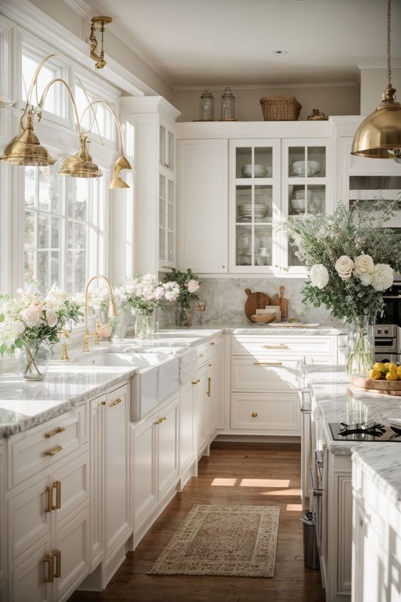 a kitchen with white cabinets and marble counter tops, gold pendant lights hanging from the ceiling