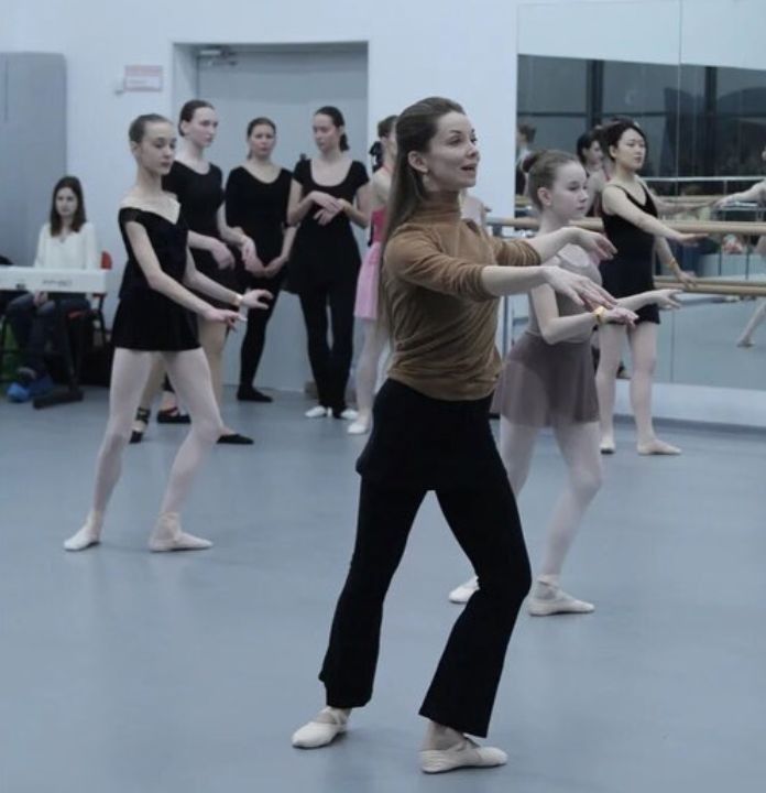 a group of people standing around each other in front of a ballerina holding a stick