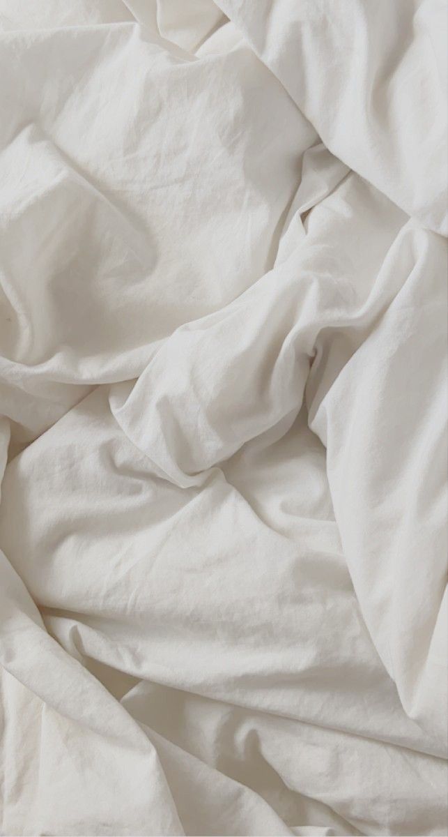 an unmade bed with white sheets and pillows