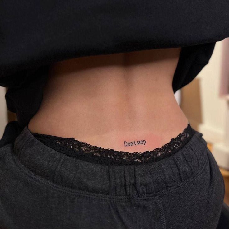 a woman with a small tattoo on her lower back that says god's food