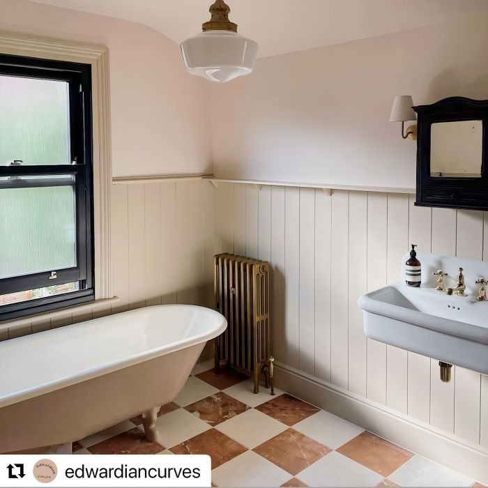 an old fashioned bathtub and sink in a bathroom with pink walls, checkered flooring and black framed windows