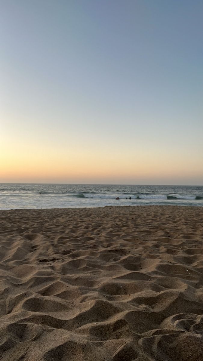 the sun is setting at the beach with waves coming in